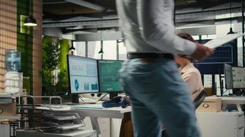 Young businesswoman focused on a podcast while she resolves office tasks, monitoring insights or KPI metrics on pc. Strategy reports for expansion plans with digital tools. Camera A. video