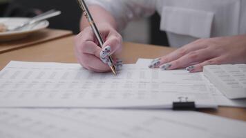 A business professional engages in data analysis by writing notes and organizing documents at a workspace. The setting features a clean desk with papers and office supplies. video