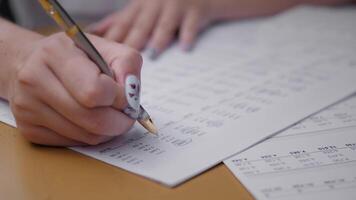 A business professional is engaged in reviewing financial documents while writing notes with a pen. The focus is on data analysis and report preparation in an office environment. video