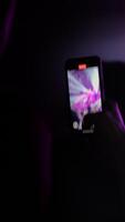 Mobile device held high, capturing dynamic live music event with vivid lighting and enthusiastic crowd, creating an engaging experience video