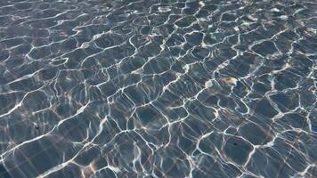 Sunlight reflecting on water surface in swimming pool with visible tile pattern. Abstract background texture. Summer vacation and relaxation concept. Design for wallpaper, banner, poster, header video