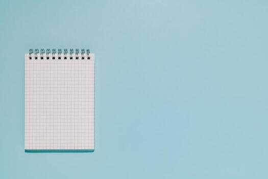 An open, blank grid notepad on a clean, light blue background. Perfect for themes of planning, ideation, learning, and new projects. photo