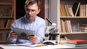 Scientist using microscope and reading tablet in laboratory video