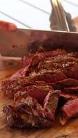 un cocinero expertamente rebanadas un jugoso carne de vaca filete en un de madera junta, destacando el carne sensibilidad y Rico color video