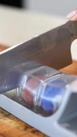 A knife is sharpened using a multi-stage sharpener on a wooden surface under bright lighting video