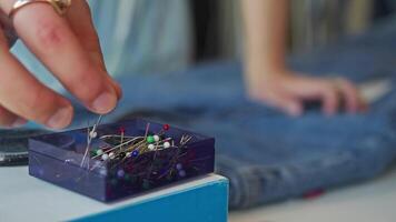 skräddare försiktigt plockar ett stift från en lugg liggande i en låda och användningar den till stift kläder medan arbetssätt i hans verkstad eller ateljé. stänga upp. video