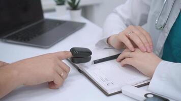 stänga upp av läkare övervakning patienter avgörande tecken använder sig av digital puls oximeter enhet under medicinsk samråd i modern sjukvård miljö med bärbar dator och anteckningsbok för digital dokumentation video