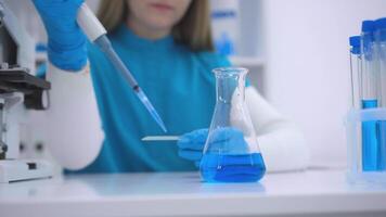 laboratório experimentar com pipeta e frasco. fêmea cientista conduzindo experimentar dentro moderno laboratório video