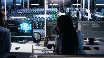 Teamworking engineers doing brainstorming in data center, reviewing AI diagnostics on computer. Team of IT expert working together in server room, optimizing artificial intelligence systems, camera A video