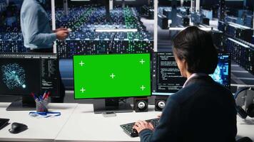 Data center software developer managing AI systems for uptime and efficiency using green screen PC. IT expert using artificial intelligence tech on mockup computer in server hub, camera A video