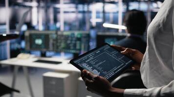 Close up of data center software developer using tablet to review code for automation scripts. Server hub IT specialist using device, monitoring error logs for debugging processes, camera A video