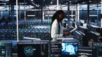 data Centrum ingenjörer hantera ai system för drifttid och effektivitet, ser över pappersarbete filer. afrikansk amerikan kvinna och asiatisk man läsning dokument i multietnisk server nav, kamera en video