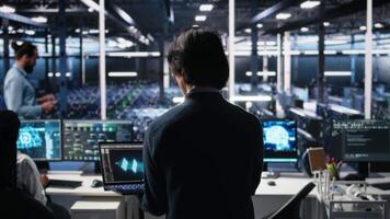 datos centrar técnico entrando oficina, gerente ai sistemas para tiempo de actividad y eficiencia. eso profesional llegando a trabajar, sentado a escritorio, utilizando artificial inteligencia en servidor centro, cámara un video