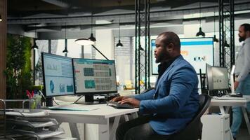 afrikanisch amerikanisch Büro Arbeiter Hebelwirkungen Analytik und Bericht Schreiben zum Entwicklung und monatlich Performance Ergebnisse, Ressourcen und Einsichten zu dafür sorgen strategisch Tore Leistung. Kamera a. video