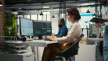 olika företags- personal arbetssätt tillsammans på Rapportera skrivning i de kontor, samarbetande på byggnad en ny utveckling strategi. granskning insikter till förbättra effektivitet och framsteg. kamera a. video