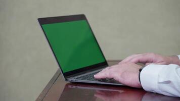 Hands of a man on a laptop keyboard with an empty green screen for inserting ideas or content video