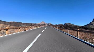 A stunningly beautiful road stretches endlessly through a breathtaking volcanic landscape beneath a clear blue video