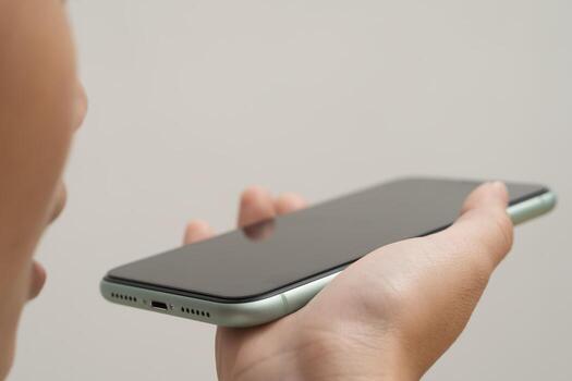 de cerca de persona Hablando dentro teléfono inteligente retenida horizontalmente para voz mando o audio mensaje utilizar foto