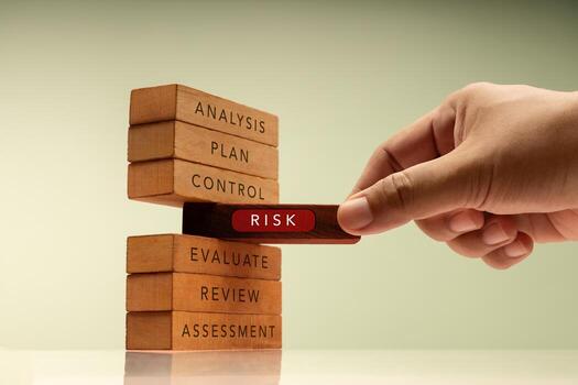 Hand pulls a block labeled RISK from stack of wooden blocks representing structured plans. Core of financial and business risk management photo