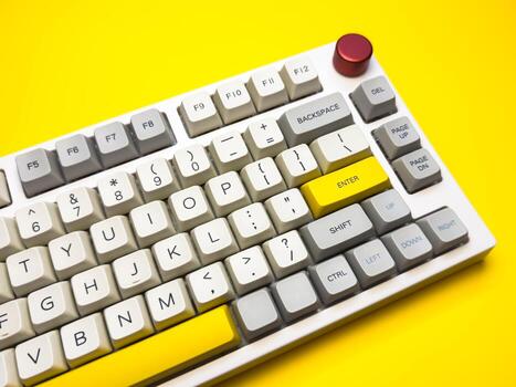White mechanical keyboard with bright Enter key on bright yellow background, minimalism, keyboard buttons photo