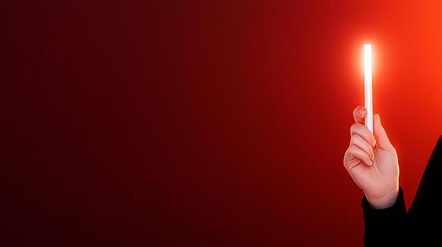 A person holding a glowing red light stick against a smooth red background, creating a striking visual effect photo