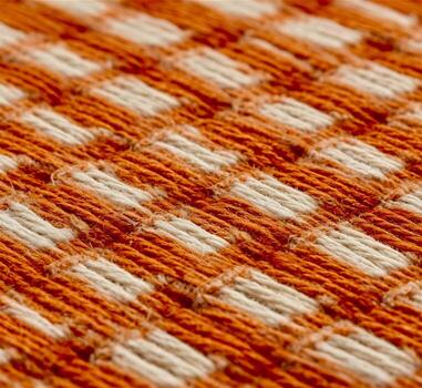 A close up of a woven fabric with orange and white squares photo