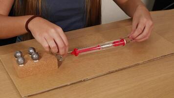 person användningar en vår skala till mäta friktions- tvinga på en viktad blockera glidning över kartong video