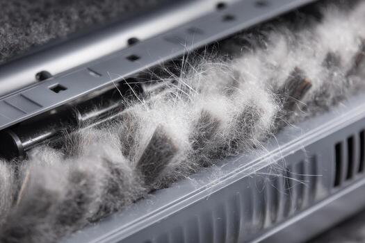 A close up view of a vacuum cleaner brush roll clogged with hair and dust after use on the carpet photo