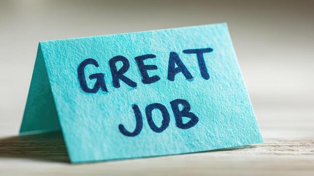 A blue paper card shows great job message written in dark ink on a bright surface closeup view photo