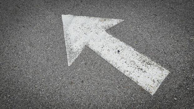 White painted arrow on asphalt road surface, representing direction and navigation in transportation photo
