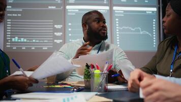 dichtbij omhoog van verschillend specialisten evalueren gegevens getallen Aan gearchiveerd bestanden, uitwisselen rapporten en inzichten naar tot stand brengen Doorzichtig onderneming doelstellingen in strategie kamer laat Bij nacht. camera a. video