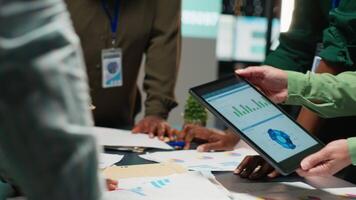 bedrijf adviseurs team vergadering na uren naar recensie diagrammen en beoordelen risico's, uitwisselen terugkoppeling en samenwerken Aan inzichten gesteund door bedrijf inlichtingen voorspelling voorspellingen. camera b. video