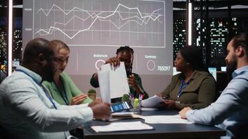 dichtbij omhoog van verschillend bedrijf personeel uitwisselen rapporten bestanden en inzichten naar voorspelling bedrijf doelstellingen in een stil strategie kamer na uren Bij nacht. financiën projecties samenwerking. camera a. video