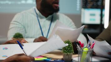 dichtbij omhoog van verschillend specialisten evalueren gegevens getallen Aan gearchiveerd bestanden, uitwisselen rapporten en inzichten naar tot stand brengen Doorzichtig onderneming doelstellingen in strategie kamer laat Bij nacht. camera b. video
