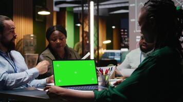 multietnisk personal arbetssätt på natt i kontor med krom nyckel på bärbar dator, säkerställa prestanda metrik analys och miljö mål för företag produktivitet. natt tid möte. kamera a. video