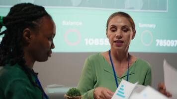 Close up of diverse staff hand over data projections papers in a meeting after hours for multinational company operations. Risk assessment and visual data to support forecasting. Camera B. video