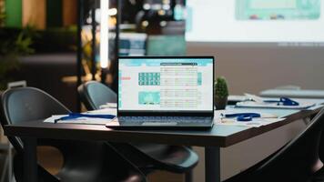 Laptop displaying digital data in a clean modern workspace in the evening, projection board forecasting insights and indicators in a boardroom. After hours administration and productivity. video