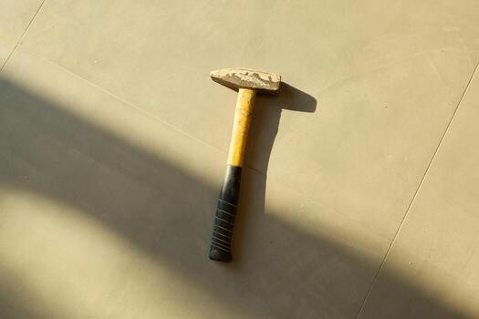Hammer on a smooth surface, casting shadows that highlight its design and functionality photo