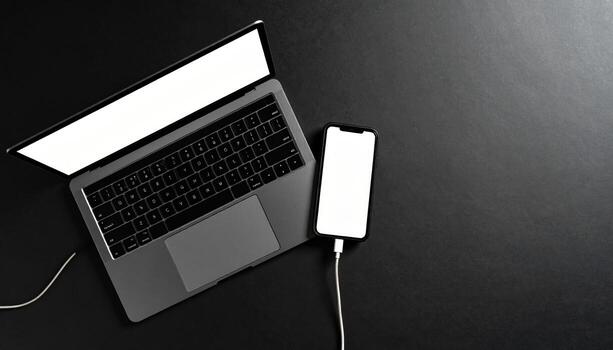 Modern minimalist laptop and smartphone on black desk. This top view technology mockup template for business content feels sleek and professional with ample copy space photo