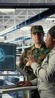 vertikal militär personal i server rum användningar ai verktyg till hjälp klara av dator system. armén team bär enhetlig recensioner information använder sig av artificiell intelligens program i server odla, kamera en video