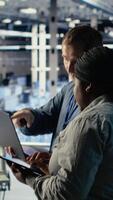 Vertical Technicians working together in server room, optimizing deep learning AI systems handling tasks. Data center coworkers doing brainstorming to adjust artificial intelligence model parameters, camera B video