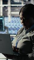 vertikal data Centrum administration checkar ai instrumentbräda använder sig av bärbar dator under riggar system recension. afrikansk amerikan kvinna i server nav tester artificiell intelligens verktyg på anteckningsbok till kolla upp pålitlig prestanda video