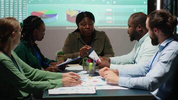 multietnisk grupp av rådgivare granskning data insikter och finansiell situation på papper, framställning uppdateringar för de aktieägare och upprättande de projekt dagordning och mål. kamera b. video