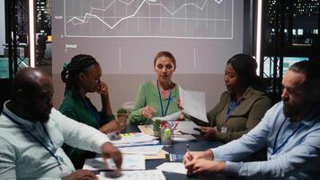 Close up of diverse business team meeting after hours for visual data reports, reviewing infographics and projections while sharing files to establish finance objectives. Business intel. Camera A. video