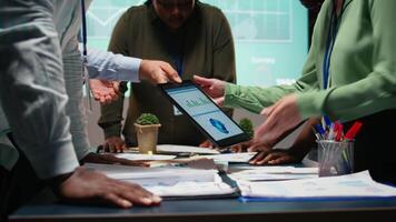 bedrijf adviseurs team vergadering na uren naar recensie diagrammen en beoordelen risico's, uitwisselen terugkoppeling en samenwerken Aan inzichten gesteund door bedrijf inlichtingen voorspelling voorspellingen. camera a. video