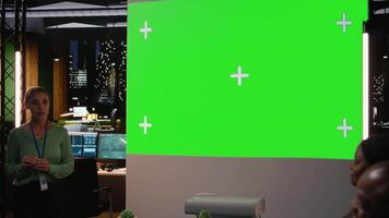 multietnisk människor samarbetande för en möte på natt med en grön skärm, analyserar tal och inriktning projekt mål. diskutera tillväxt strategi i ett verkställande kort efter timmar. kamera a. video