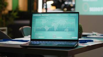 vuoto sala del consiglio con un' il computer portatile in esecuzione prestazione metrica e dati proiezioni su schermo nel silenzioso buio ufficio, impostato per un' notte incontro a un' multinazionale azienda preparazione per attività commerciale crescita. video