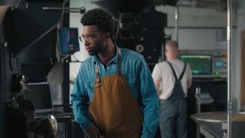 pequeño negocio propietario africano americano hombre operador gerente comprobación calidad trabajo proceso en café asado tela comprobación asado cacao máquina sonriente a cámara posando cruzado manos masculino chico sonrisa video