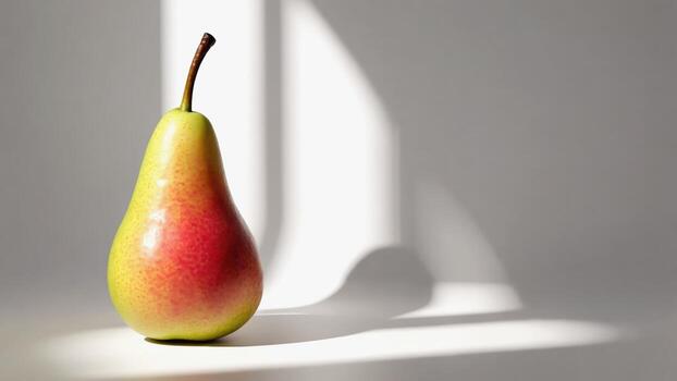 Juicy pear with green and red halves on a light background. Shadows and light stripes create an interesting visual effect. Ideal for culinary and fitness projects. photo