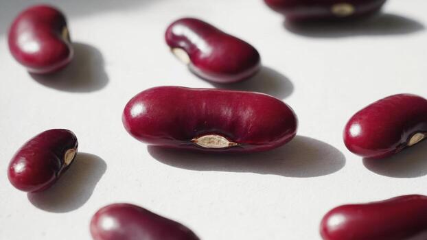 rojo frijoles son metido en un blanco fondo, iluminado por brillante luz, creando claro oscuridad. el suave textura y distintivo forma hacer esta imagen atractivo foto